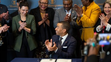 Steven Reed and several others applaud at a bill signing